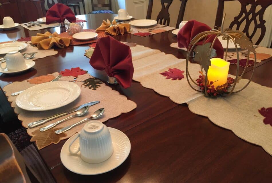 Table setting with white dishes, fall decor and a candle burning