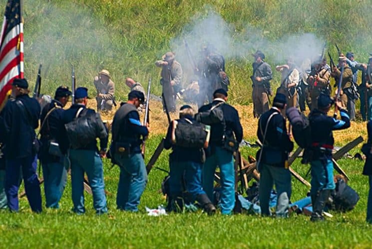 A group of men dressed in Civil War costume reenacting a scene outdoors
