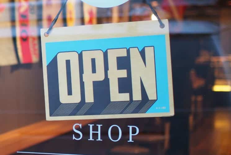 A rectangular shop sign hanging on a door window with the word 