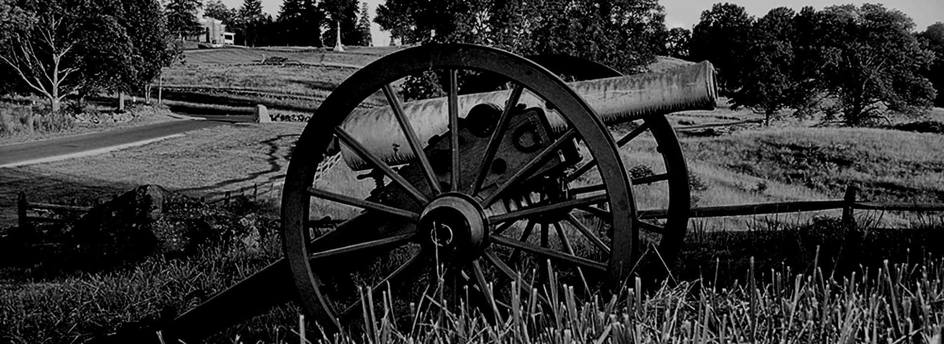 Old historic cannon in a field of green grass with farmland behind