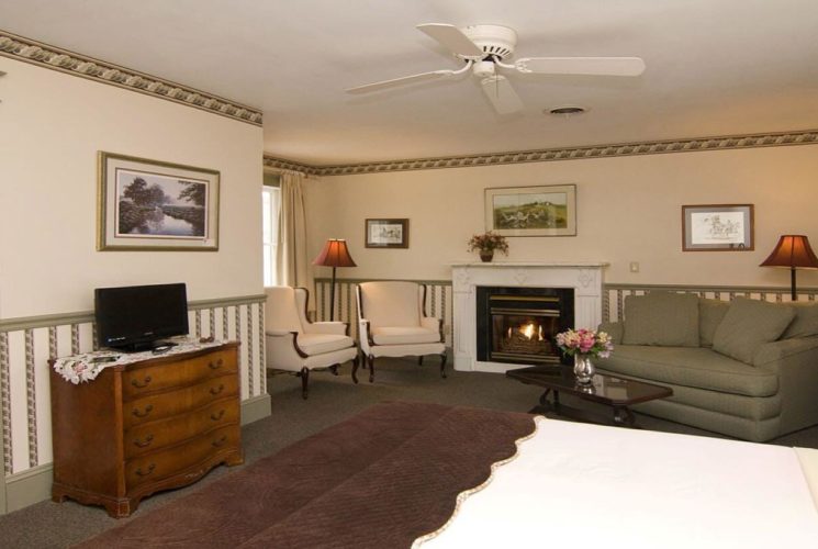 Bedroom featuring large sitting area with loveseat, white chairs, and gas fireplace