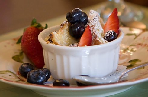 Small white dish with bread pudding, strawberries and blueberries