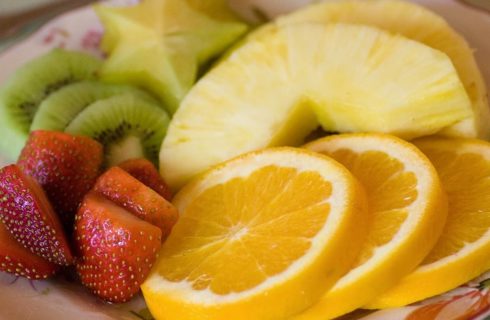 Flowered plate with cut oranges, strawberries, kiwi, pineapple and starfruit