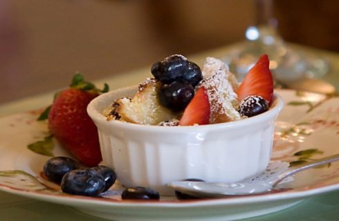 Small white dish with bread pudding, strawberries and blueberries