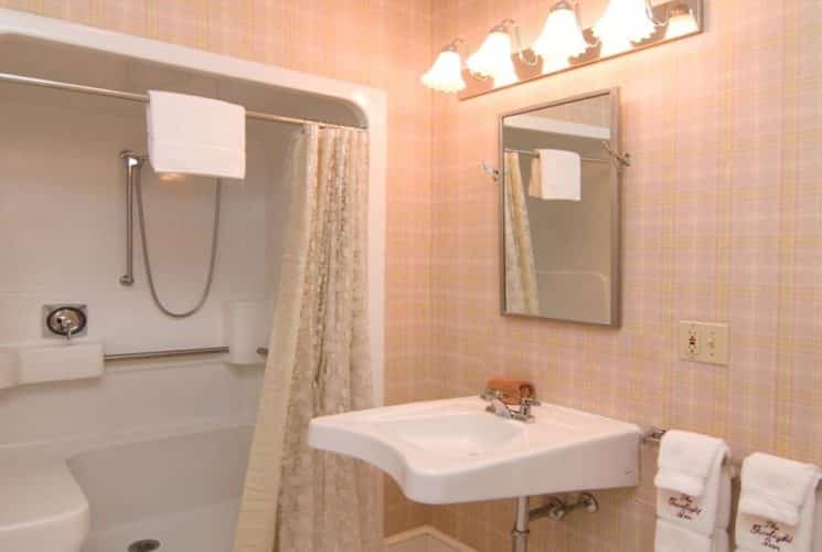 Bathroom with plaid wallpaper, large shower, and single white sink