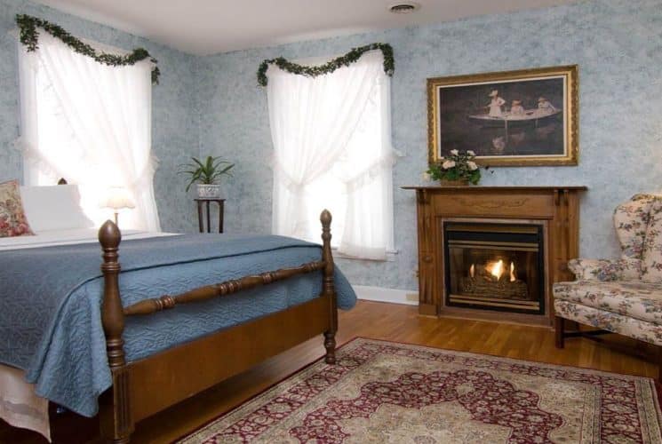 Guestroom with queen bed, gas fireplace and wingback sitting chair