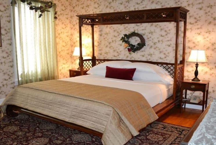 Guestroom with king bed, side tables with lamps, flowered wallpaper and window