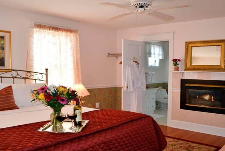 Romantic bedroom with king bed, gas fireplace and door open to bathroom with two hanging robes