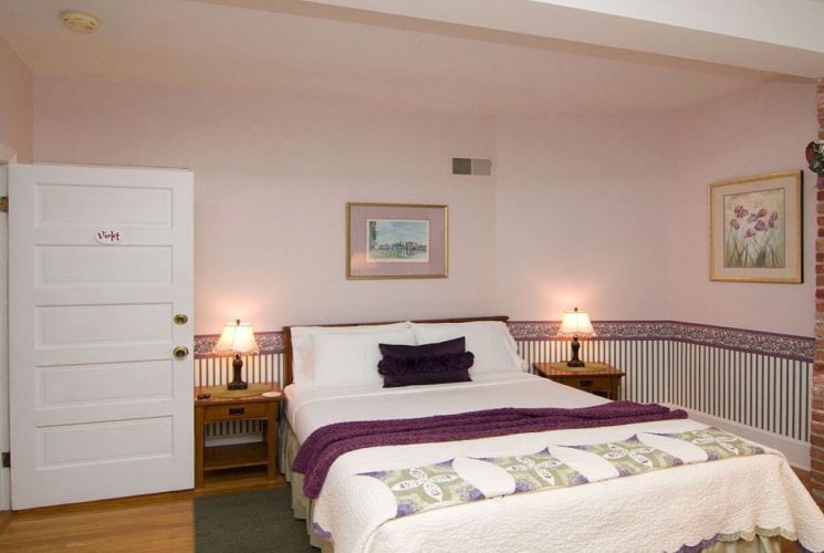 Guest room with queen bed, side tables with lamps and brick wall feature