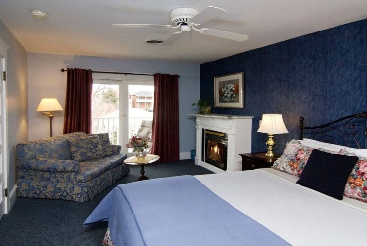 Bedroom with blue walls, queen bed, couch and coffee table and gas fireplace