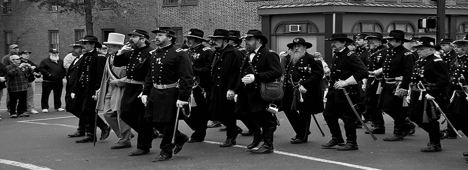 A large group of soldiers dressed in Civil War uniform walking down a street