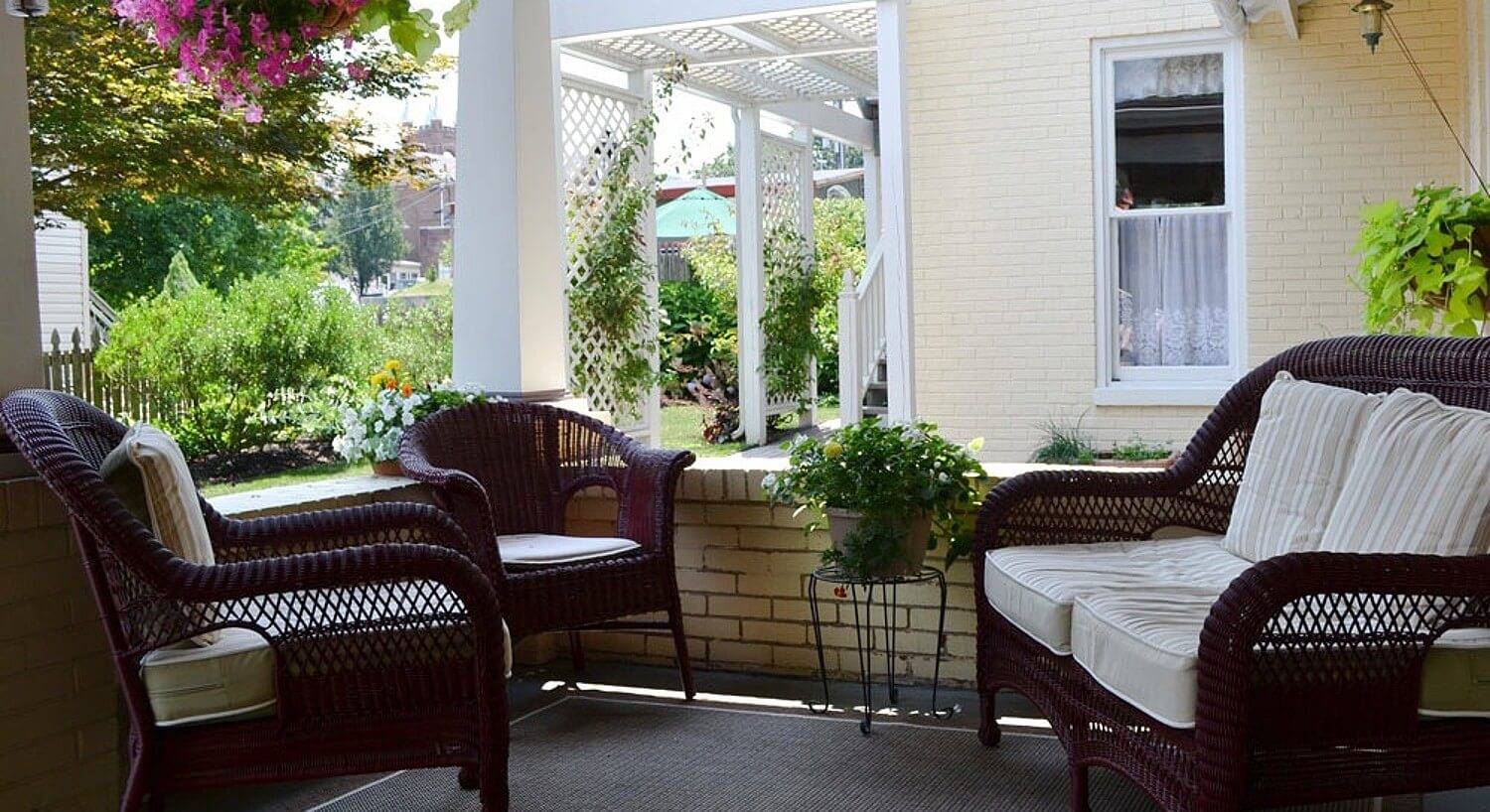 Outdoor patio with brown wicker furniture, white columns and plants