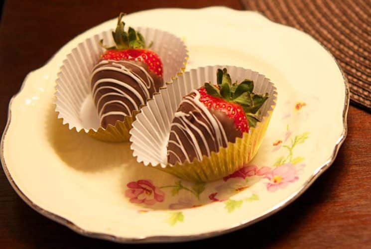 Two chocolate covered strawberries on a round flowered plate