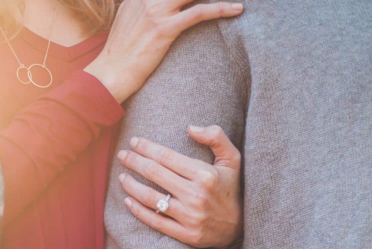 A woman in red holding on to the arm of a man in a grey sweater