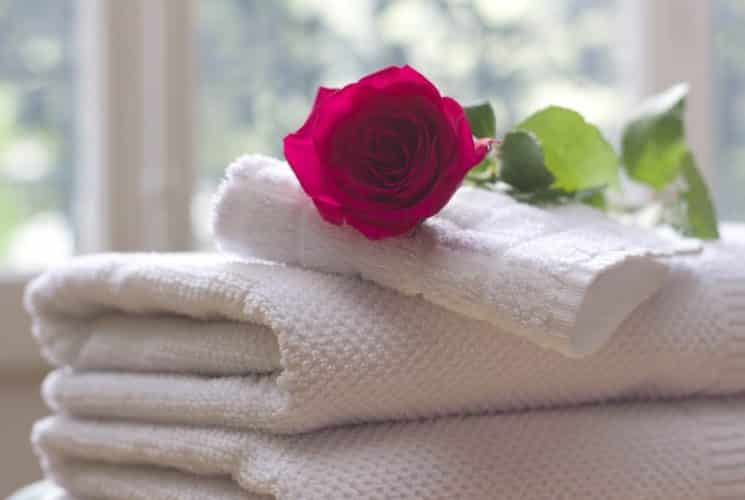 White towels folded and stacked with a single red rose on top